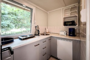 A compact kitchen with a window, a toaster, a kettle, and a microwave.