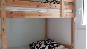 A bunk bed with a patterned pillow in a room with white walls and a door. - Gemütliches, 30 qm Großes Ferienhaus für 4 Personen. - Minna-busch-weg (Loddin)