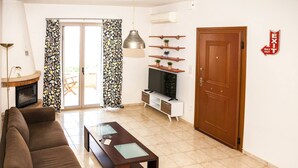 A living room with a sofa, a coffee table, a TV, and a fireplace. - Family Villa Hera With Sea View (Mylopotamos)