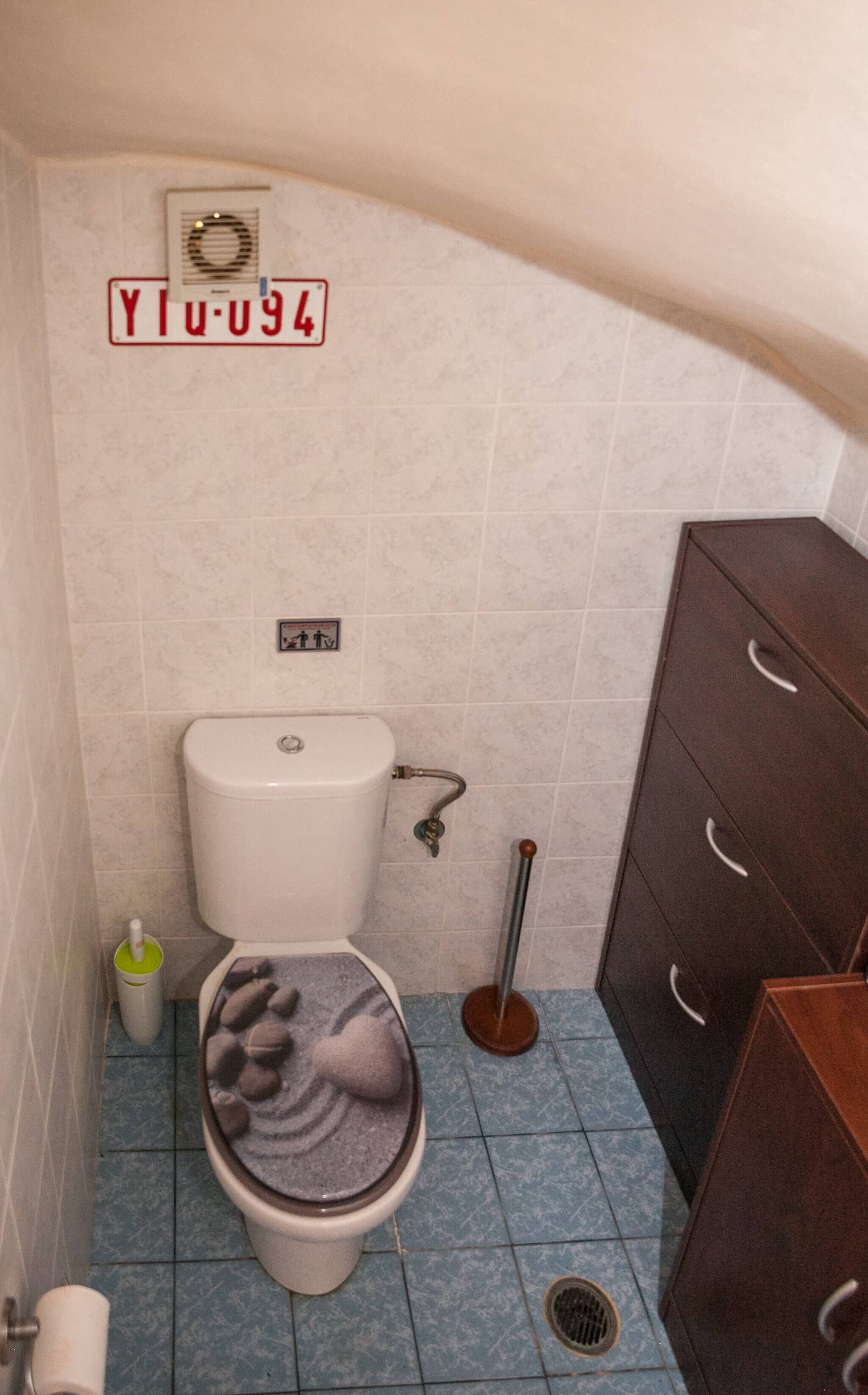 A small bathroom with a toilet, a bidet, a mop, and a cabinet.
