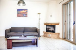 A living room with a sofa, a coffee table, a fireplace, and a painting on the wall.