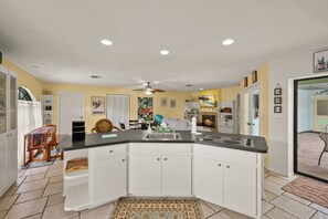 Kitchen with stove, sink, and ceiling fan, adjacent to a dining area with a table and chairs.