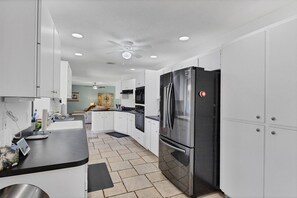Enjoy cooking in this well-equipped kitchen with a black refrigerator, black countertop, and tiled floor.