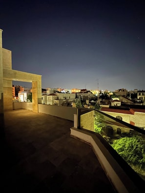 A nighttime view of a residential area with buildings and a balcony with a glass railing.