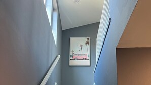 A staircase with wooden steps and white railings, leading to a landing with a framed picture on the wall.
