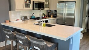 A modern kitchen with a large island, stainless steel appliances, and bar stools.