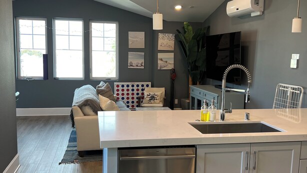 A modern kitchen with a central island, built-in dishwasher, and a large window.