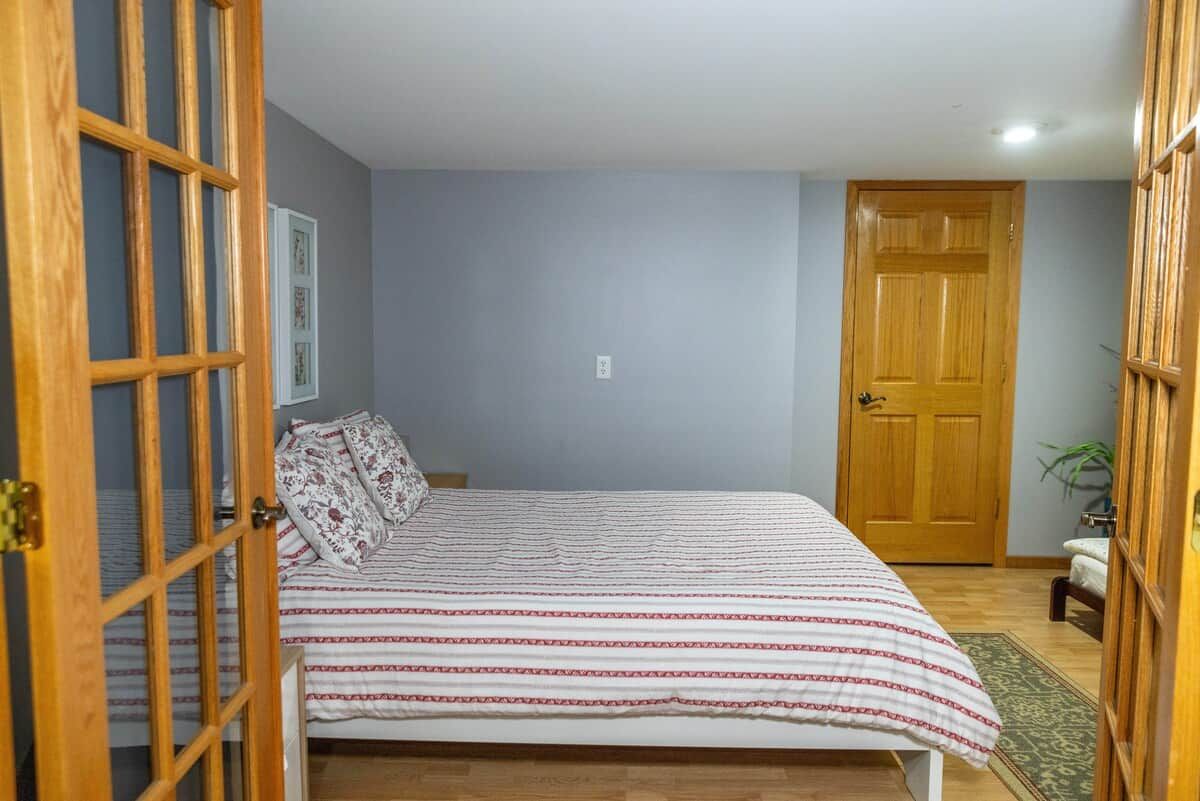 Ein Schlafzimmer mit einem Bett, einer Holztür und einer kleinen Pflanze.