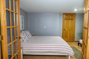 Ein Schlafzimmer mit einem Bett, einer Holztür und einer kleinen Pflanze.