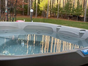 Ein Whirlpool mit freiem Blick auf die umliegenden Bäume und eine Rasenfläche.