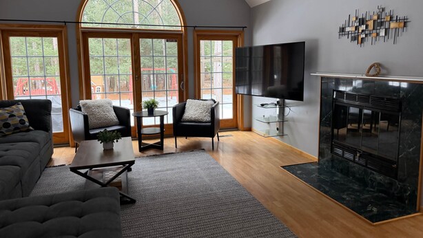 A modern living room with a fireplace, large windows, and a TV.