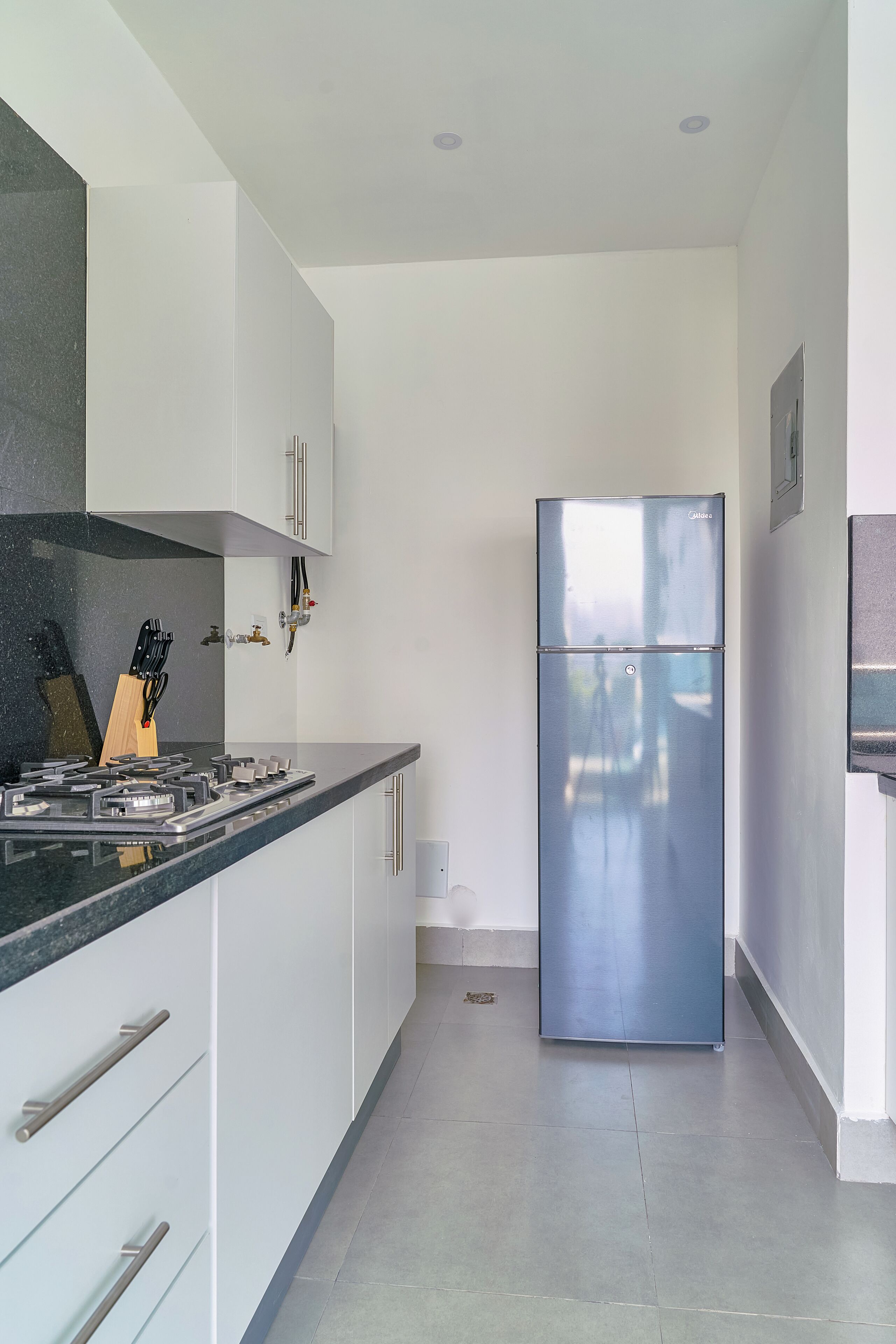 A modern kitchen with white cabinets, a stainless steel refrigerator, and a gas stove.