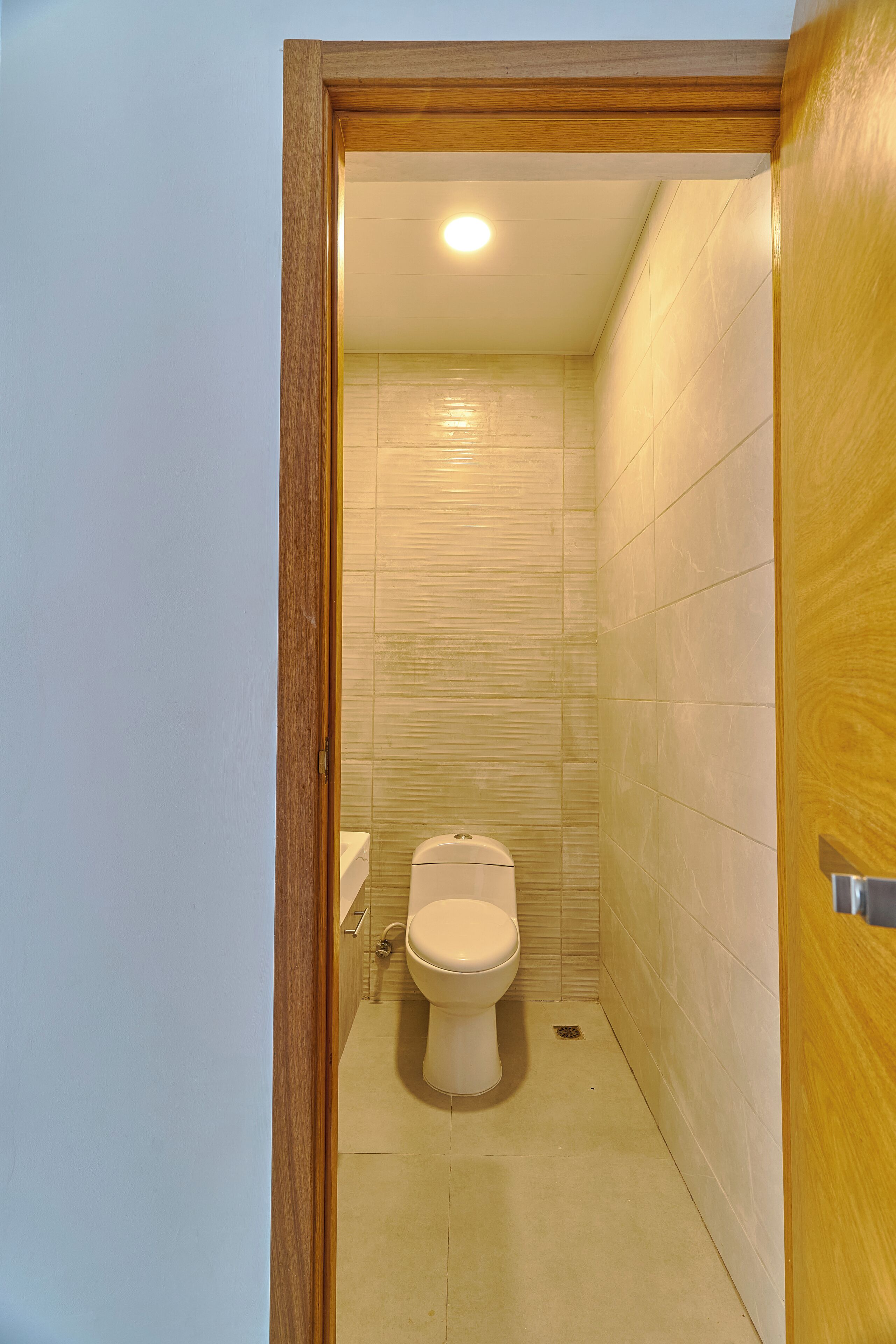 Een kleine, smalle badkamer met toilet, wastafel en douche.