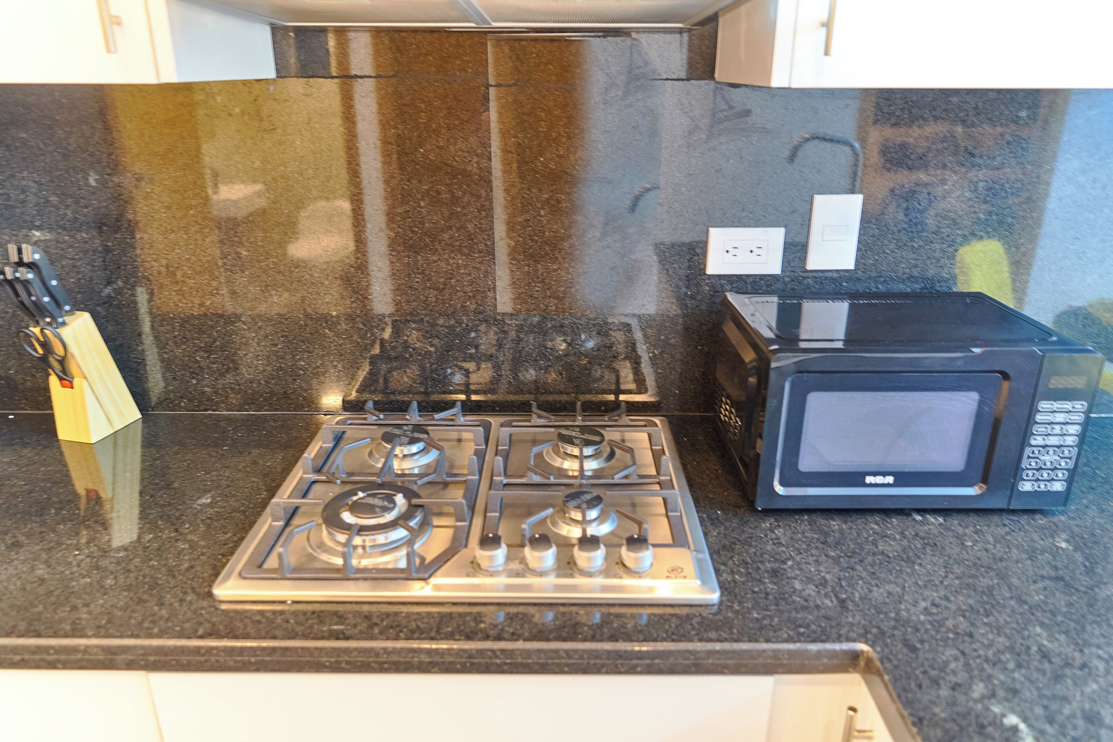 A kitchen with a gas stove and a microwave on a granite countertop.