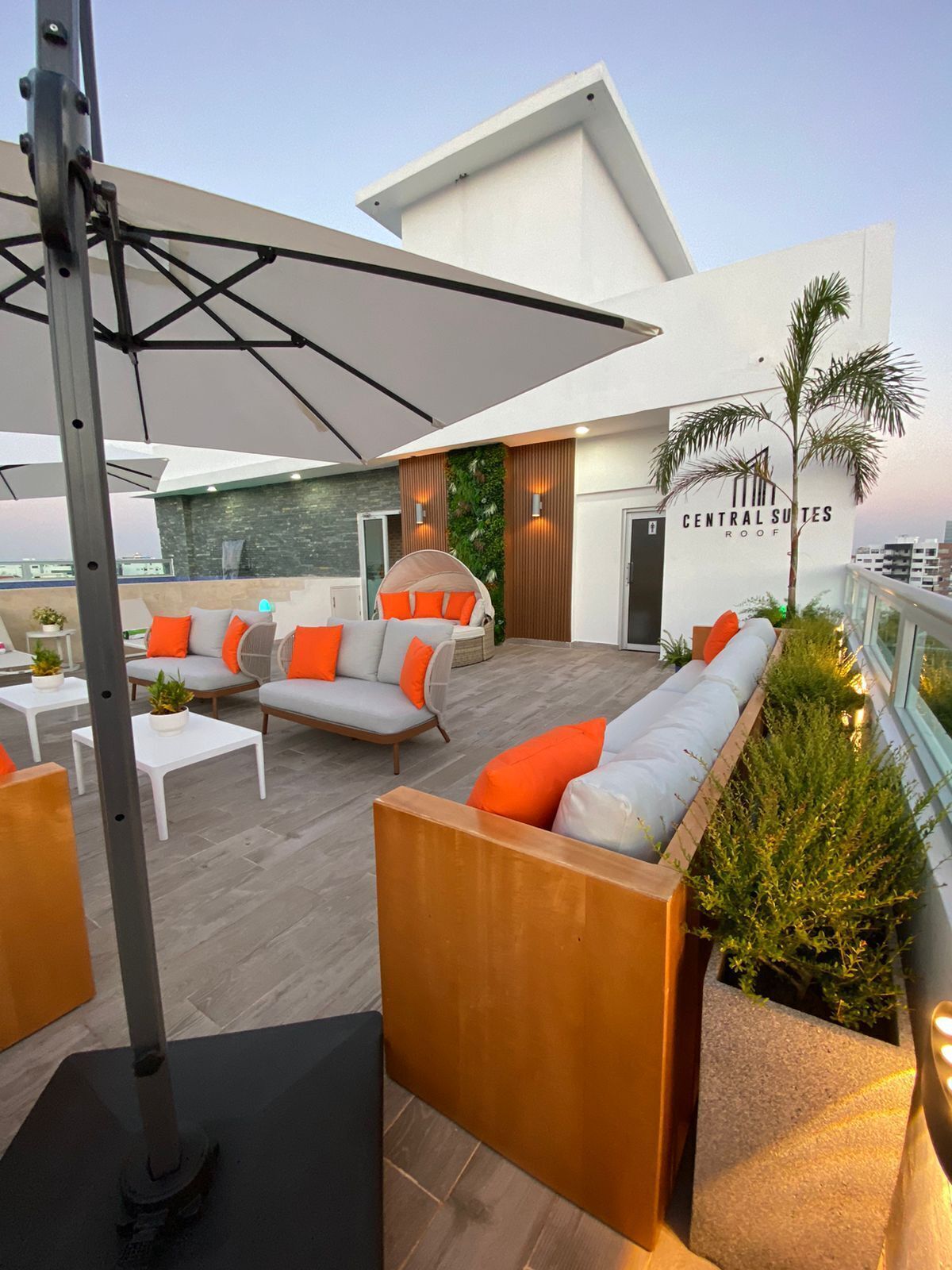 Een terras op het dak met zitgedeeltes, een grote parasol en een bordje met de tekst 'Central Suites Roof'.