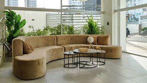 A modern living room with a curved sofa, a small round table, and a hanging light fixture. - Central Suites Tower (Santo Domingo)