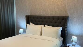 Une chambre d’hôtel avec un grand lit, deux tables de chevet avec des lampes, un climatiseur fixé au mur et un rideau à la fenêtre.