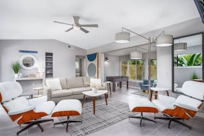 A modern living room with a sofa, armchairs, a coffee table, and a foosball table.