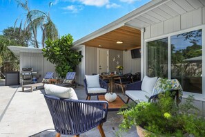 Een terras buiten met een eethoek, lounge stoelen en een barbecuehoek.