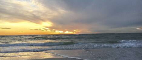A beach with waves and a sunset.
