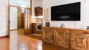 Cucina moderna con mobili in legno, forno integrato e un ampio televisore a schermo piatto montato a parete.