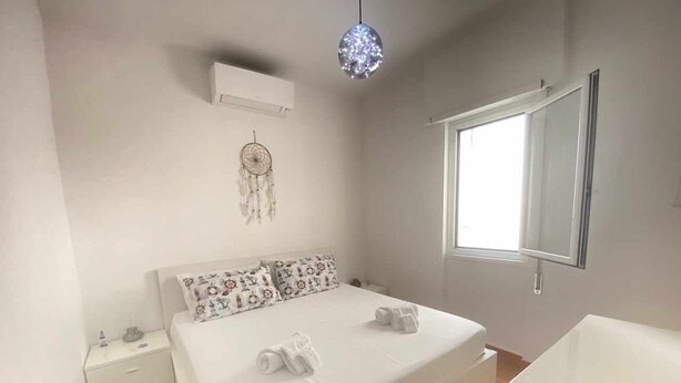 Una camera da letto con un letto, un comodino, un'acchiappasogni e un'ampia finestra.