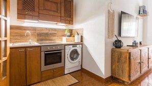 Una cucina compatta con mobili in legno, una lavatrice e un forno integrato.