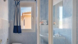 A bathroom with a toilet, a sink, and a shower area. - Stunning Views of Baia de Bahas Residence 1 Bedroom Sleeps 4 (Golfo Aranci)