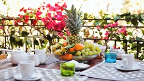 A table set with white teapots, cups, and a bowl of fruit including pineapple, oranges, and grapes. - Stunning Views of Baia de Bahas Residence 1 Bedroom Sleeps 4 (Golfo Aranci)