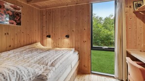 A wooden room with a bed, a window, and a door leading outside.