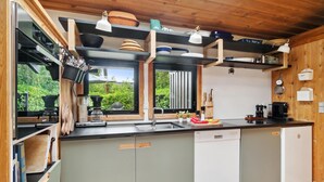 A modern kitchen with a built-in dishwasher, wooden cabinets, and a window overlooking greenery.