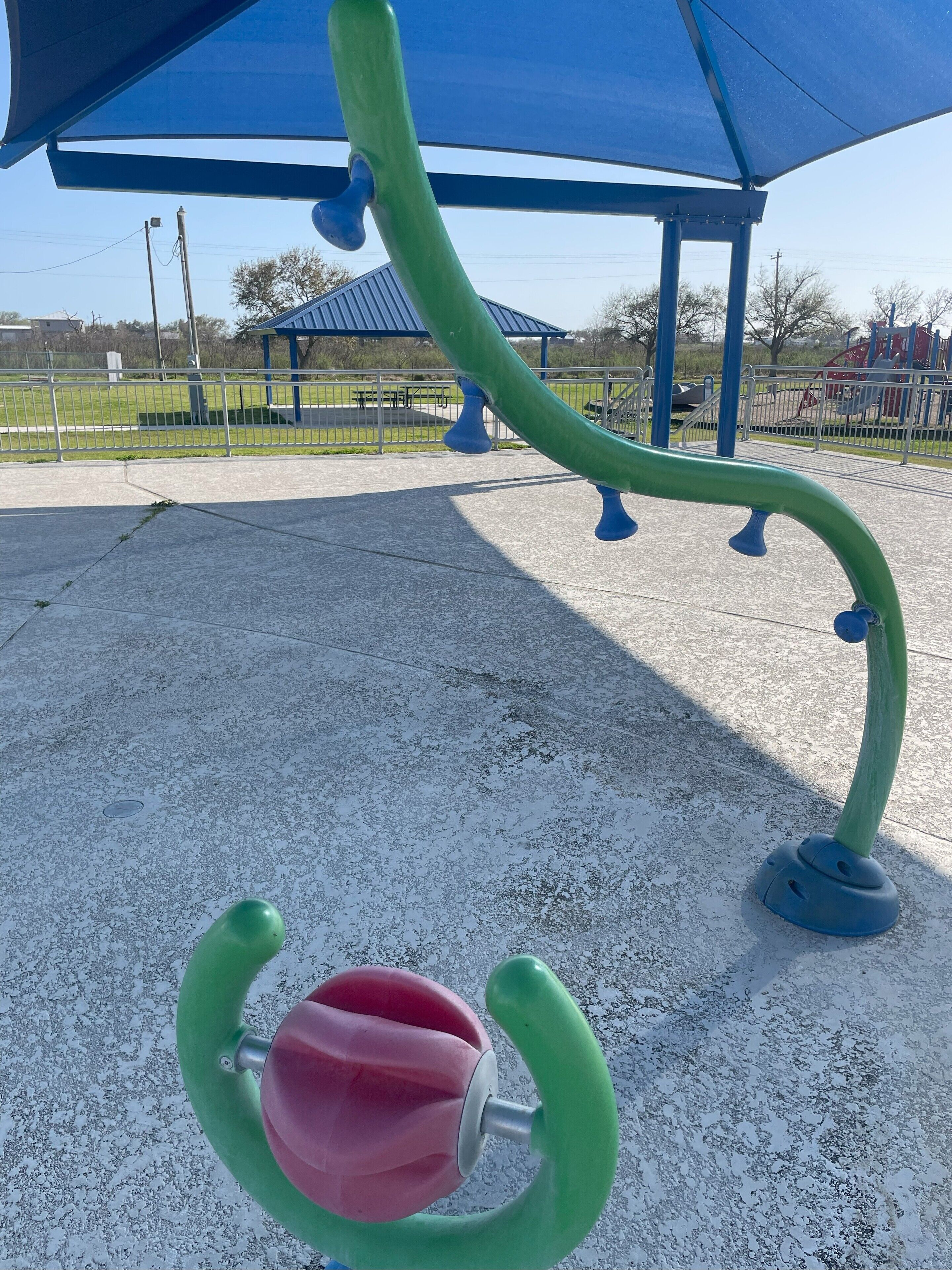 A playground structure with a green slide and a red circular element.