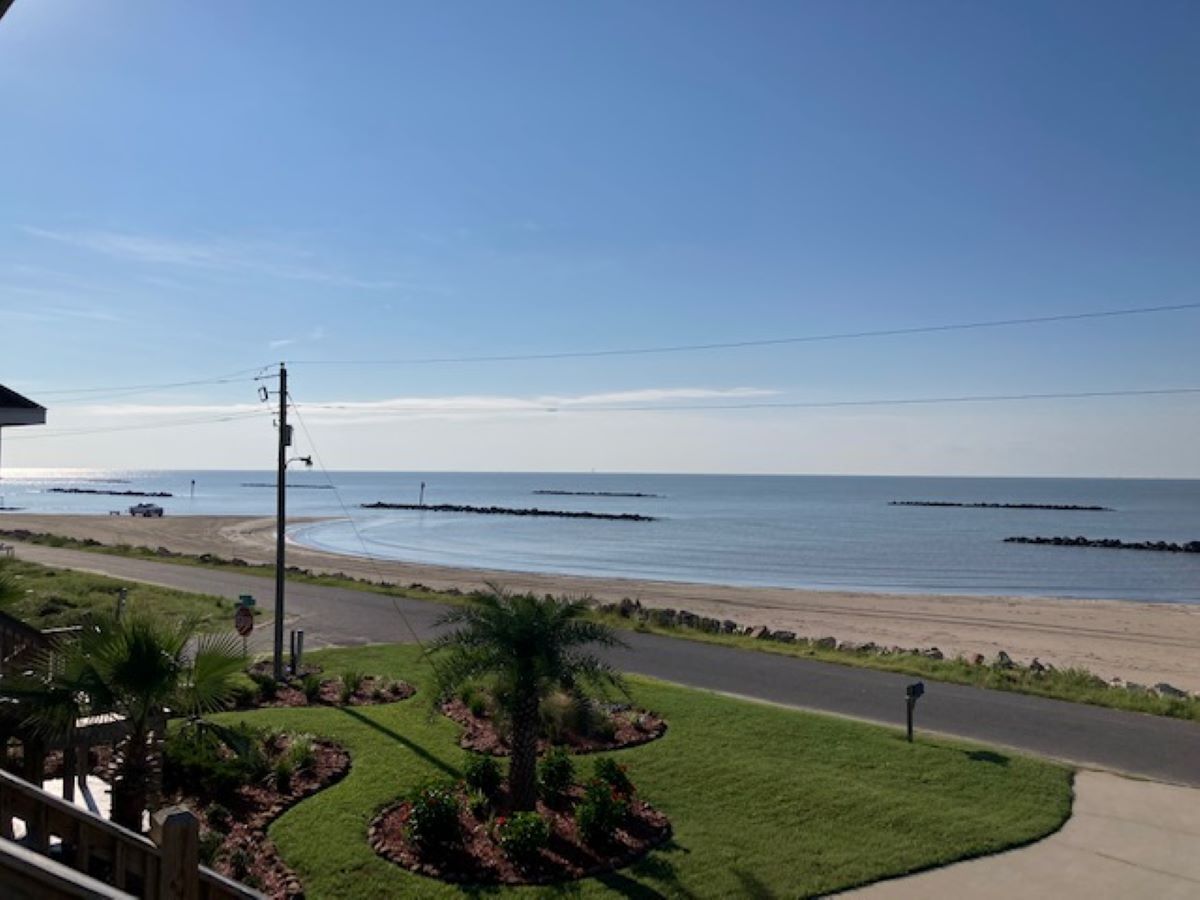 Une vue sur la côte, avec une route menant à une plage, des palmiers et un ciel dégagé.