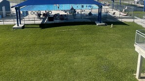 Une piscine surmontée d’un toit bleu, une tour à eau et une zone herbeuse.
