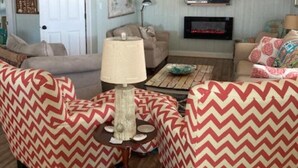 Un salon avec deux fauteuils, une table basse, une lampe, un téléviseur et une cheminée.