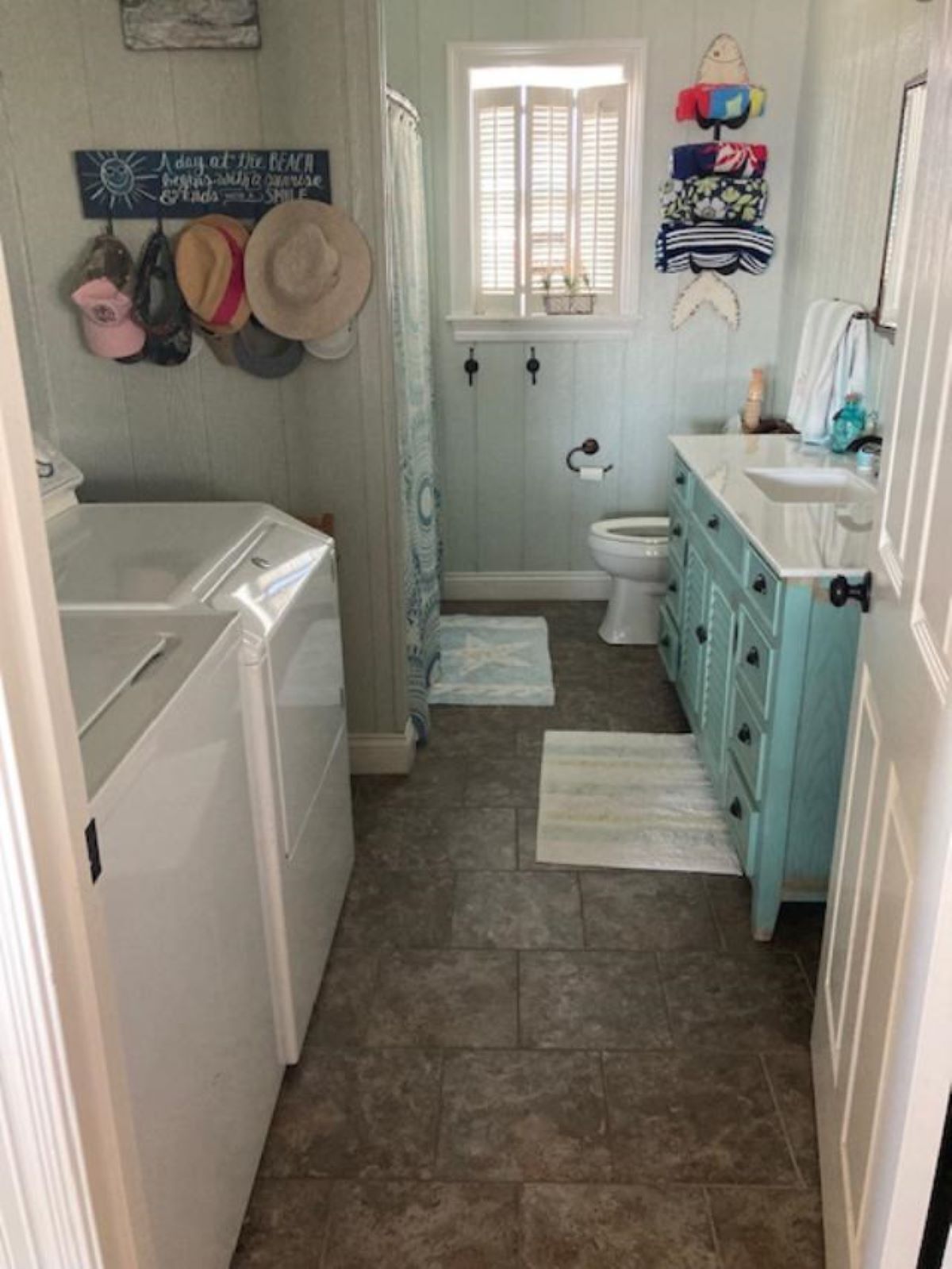 A compact bathroom with a washing machine, a toilet, and a sink with a vanity.