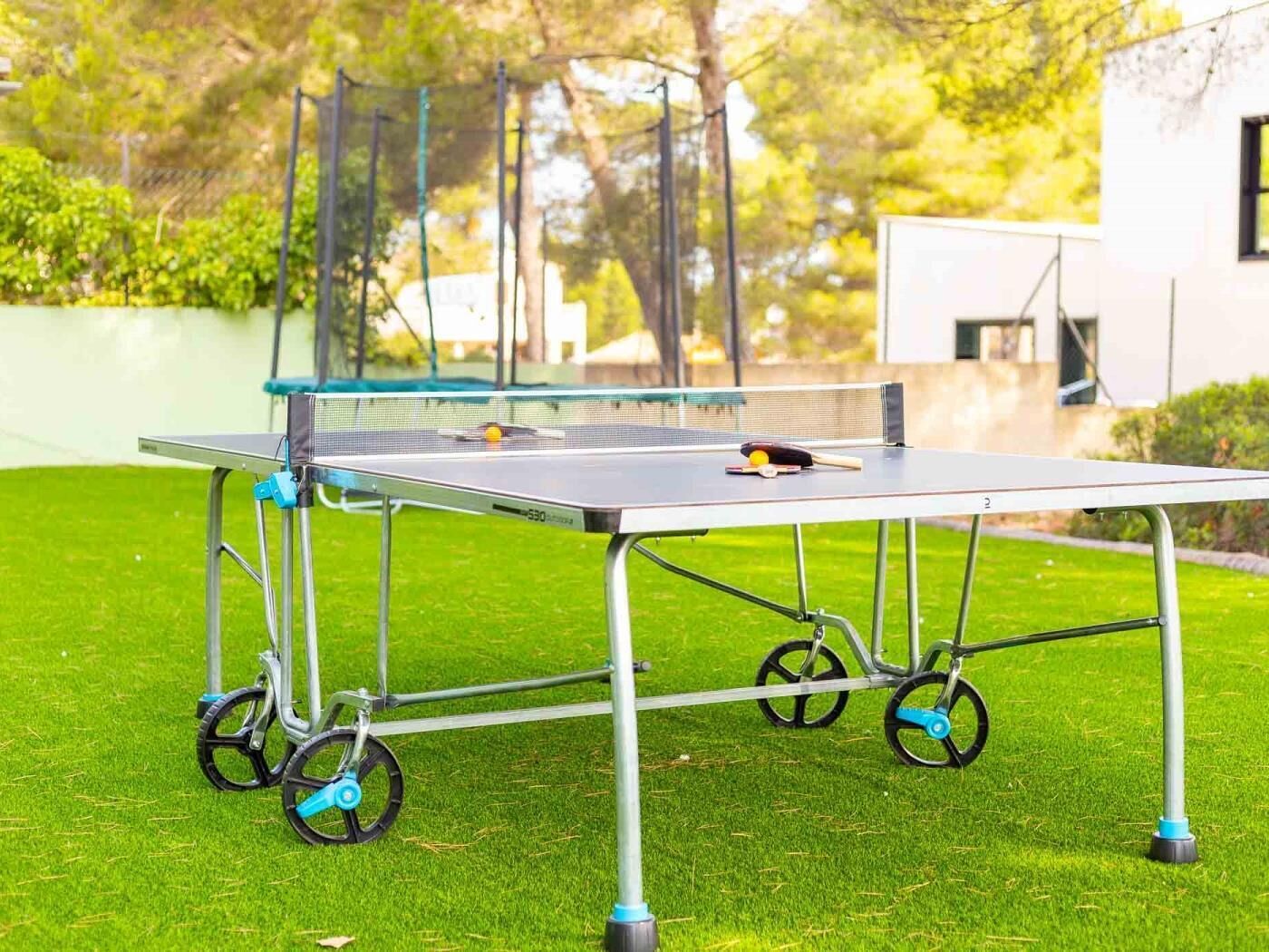 Una mesa de ping pong portátil sobre ruedas, montada en un césped.