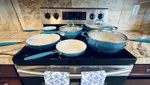 Une cuisine équipée d’une cuisinière, de casseroles et d’un torchon à motifs suspendu au-dessus du four.