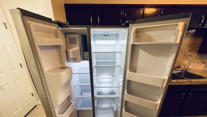 Un réfrigérateur ouvert, doté de plusieurs étagères et d’un distributeur d’eau.