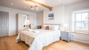 Un dormitorio con una cama grande, una mesita de noche, un ventanal con vistas y una viga de techo de madera.