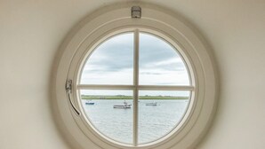 Una ventana circular con vistas a un cuerpo de agua tranquilo y barcos.