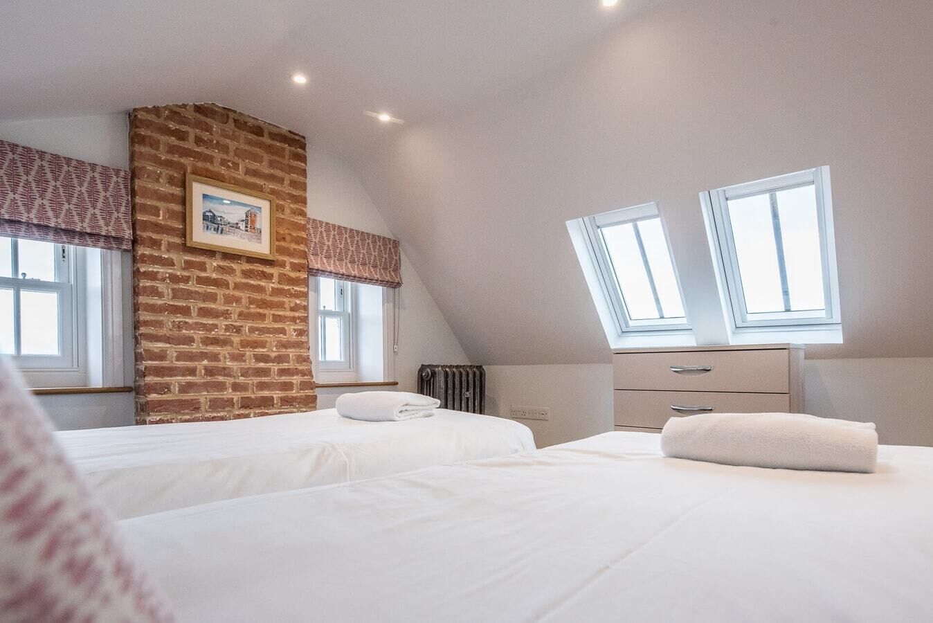 Ein Schlafzimmer mit zwei Betten, einer Backsteinwand, einem Heizkörper und einem Fenster mit Blick.
