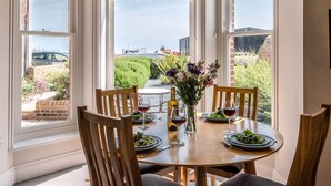 A dining table set for four with a view of a garden and a car in the background. - Trehafod, Aldeburgh (Aldeburgh)