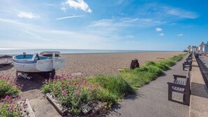 Une plage avec des bateaux, un sentier et une rangée de bancs.