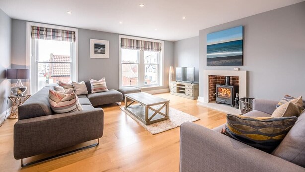 A modern living room with a grey sofa, a wooden coffee table, and a fireplace. - Lyndhurst, Aldeburgh (Aldeburgh)