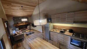 Eine moderne Küche mit Holzausbau, einem eingebauten Backofen und einer Essecke mit einer Bank und einer Couch.