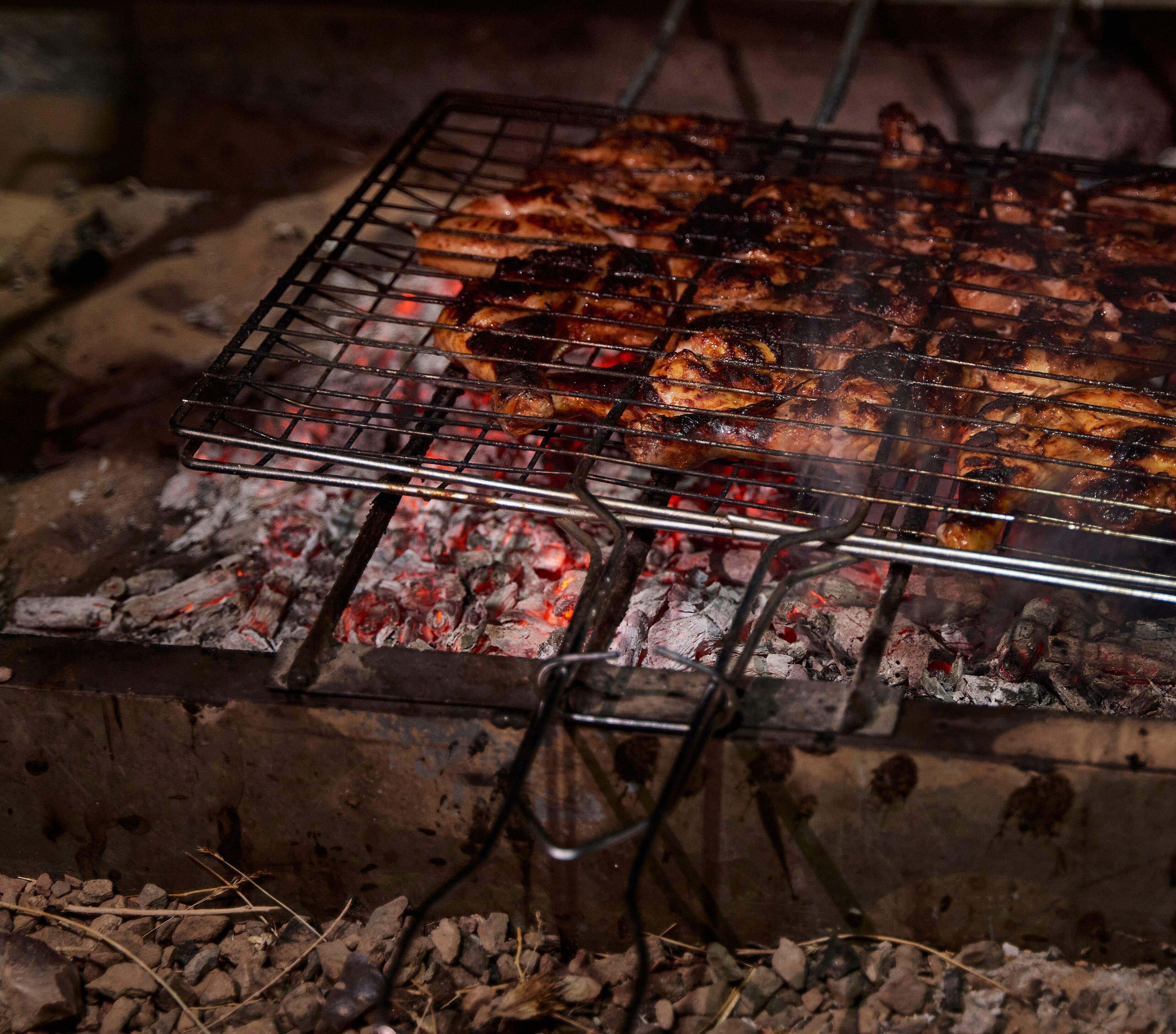 A grill with meat being cooked over charcoal.