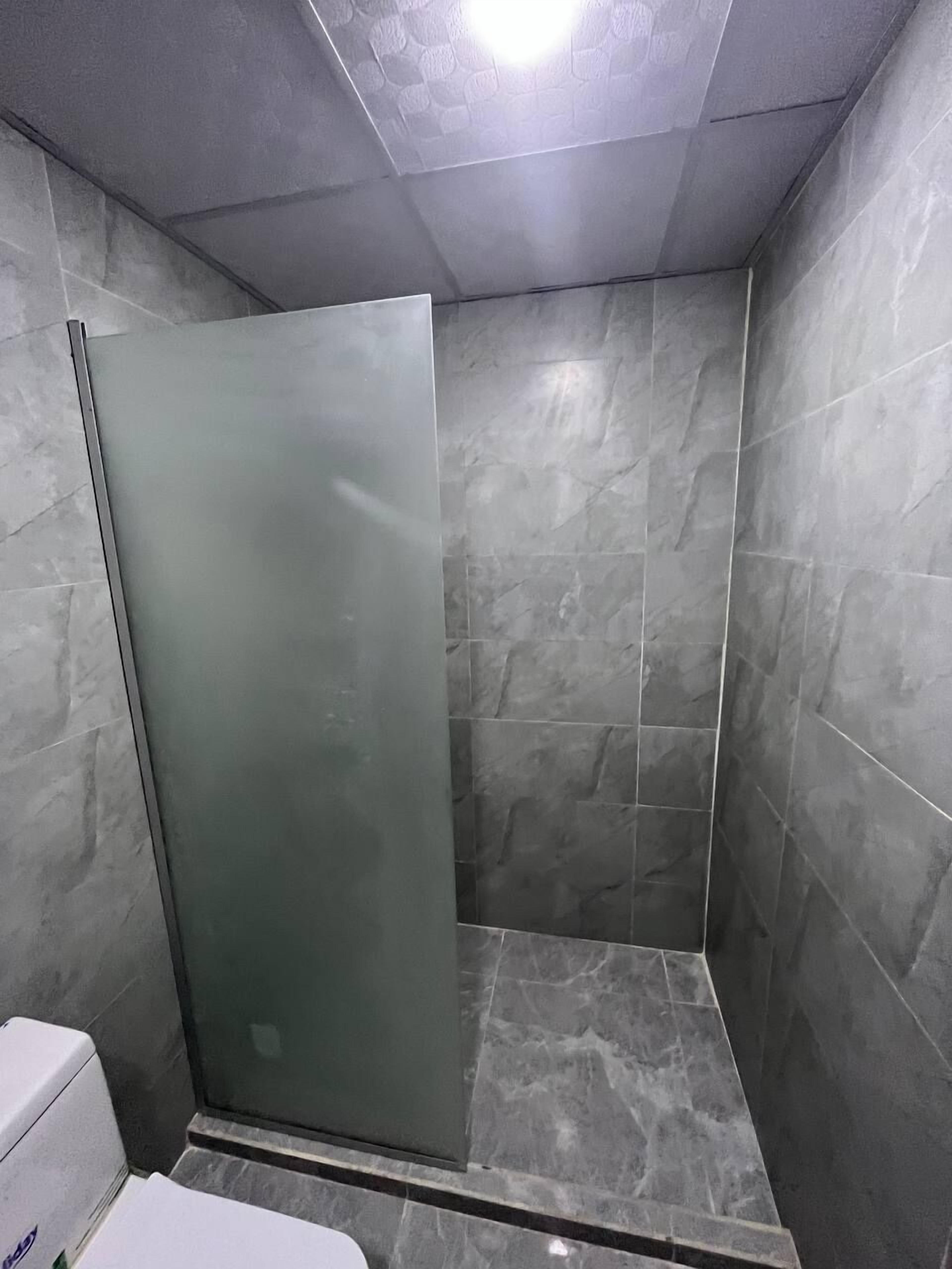 A small, enclosed shower area with a glass door and tiled walls.