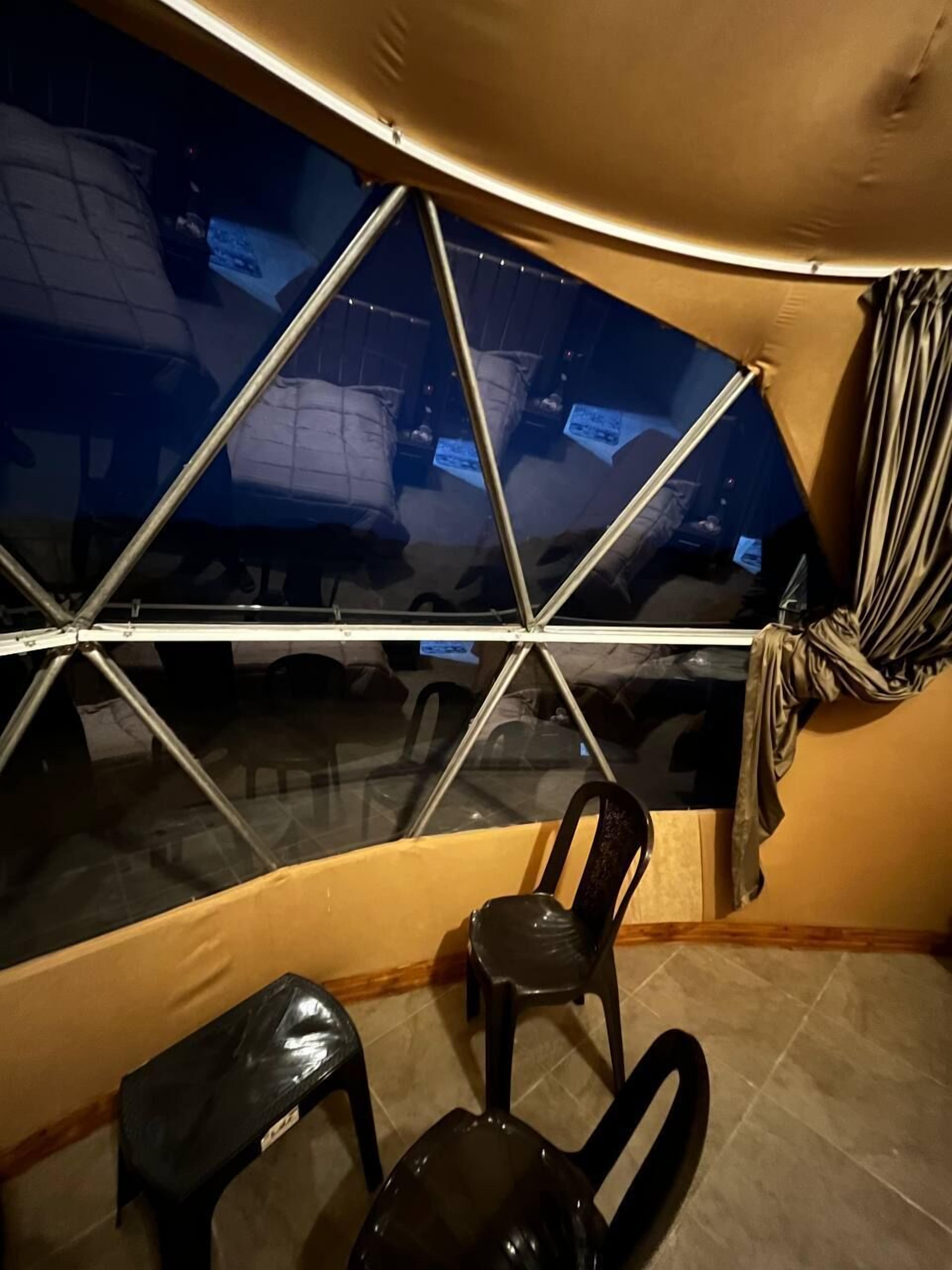 Una habitació amb una finestra gran, una cadira i una taula petita.