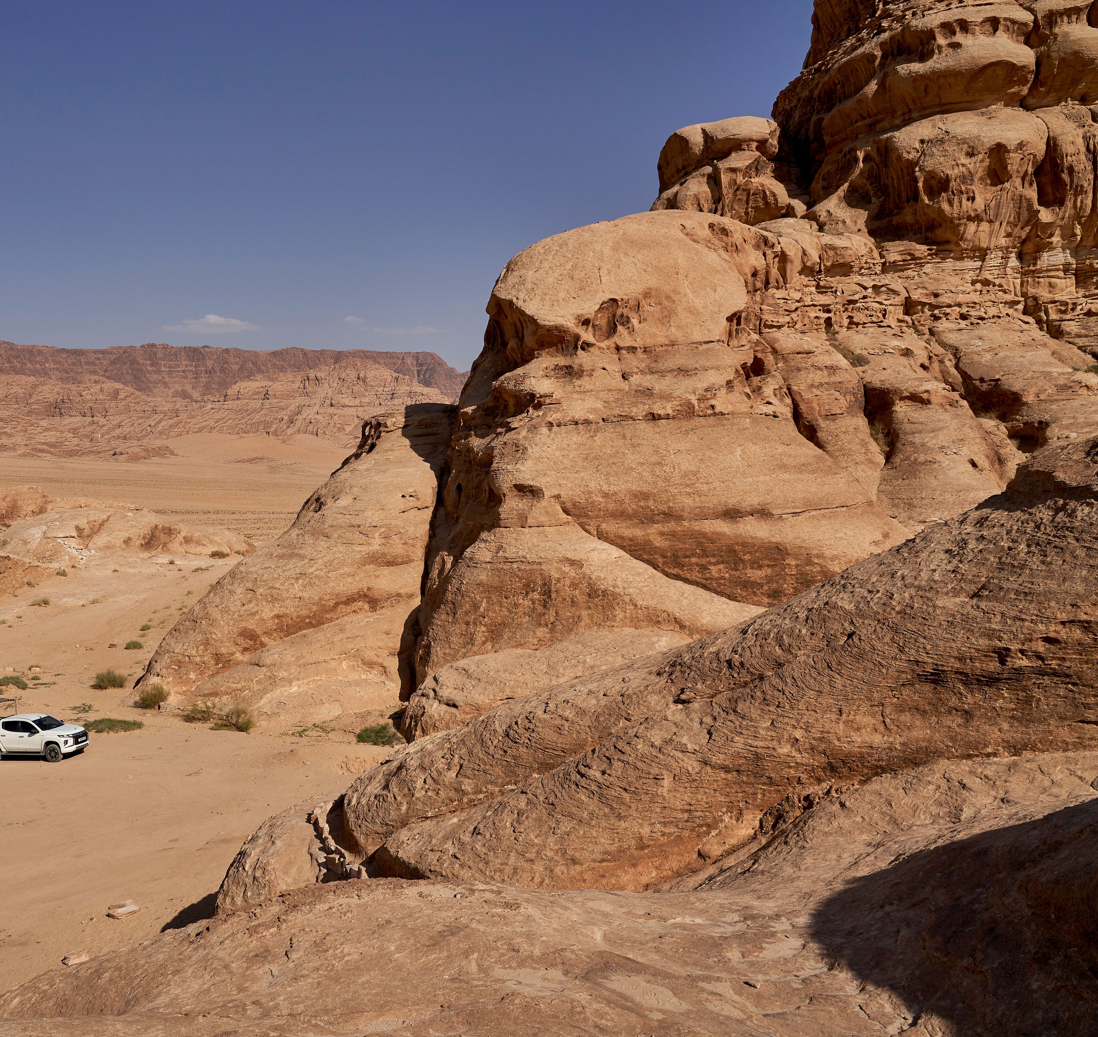 A desert landscape with rocky formations and a white vehicle.